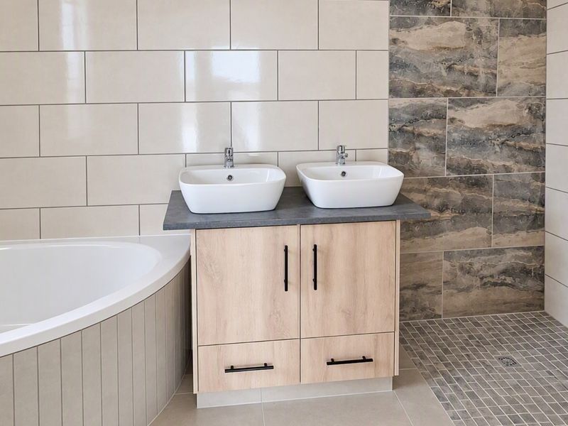 Modern bathroom featuring a double vanity with vessel sinks, a corner bathtub, and a spacious walk-in shower with contemporary tile finishes.