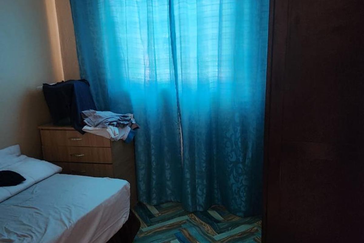 A bedroom featuring patterned flooring and a window with blue curtains.