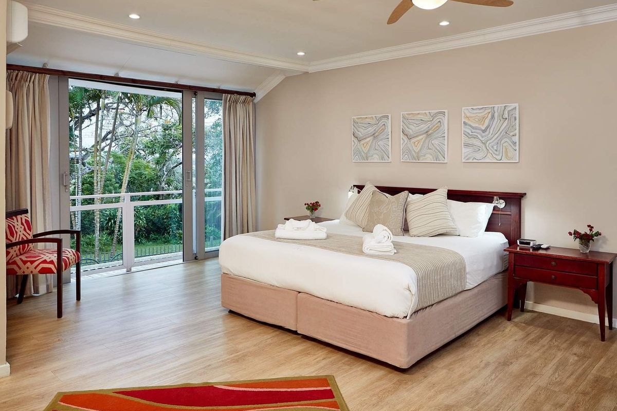 Spacious bedroom featuring laminate flooring, recessed lighting, a ceiling fan, and direct access to a private balcony through sliding glass doors.