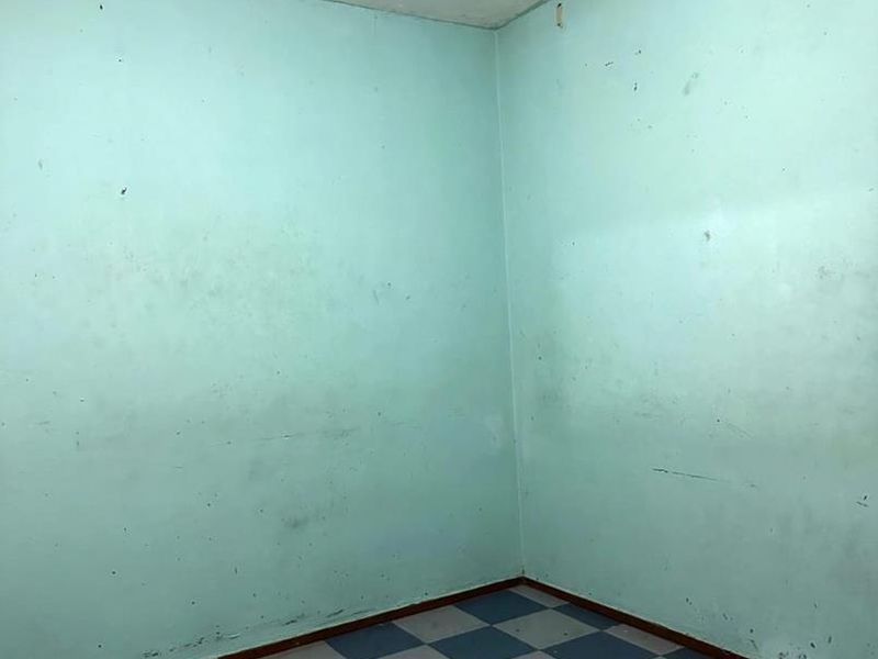 An empty bedroom featuring checkered vinyl flooring and walls in need of repainting and cosmetic repair.