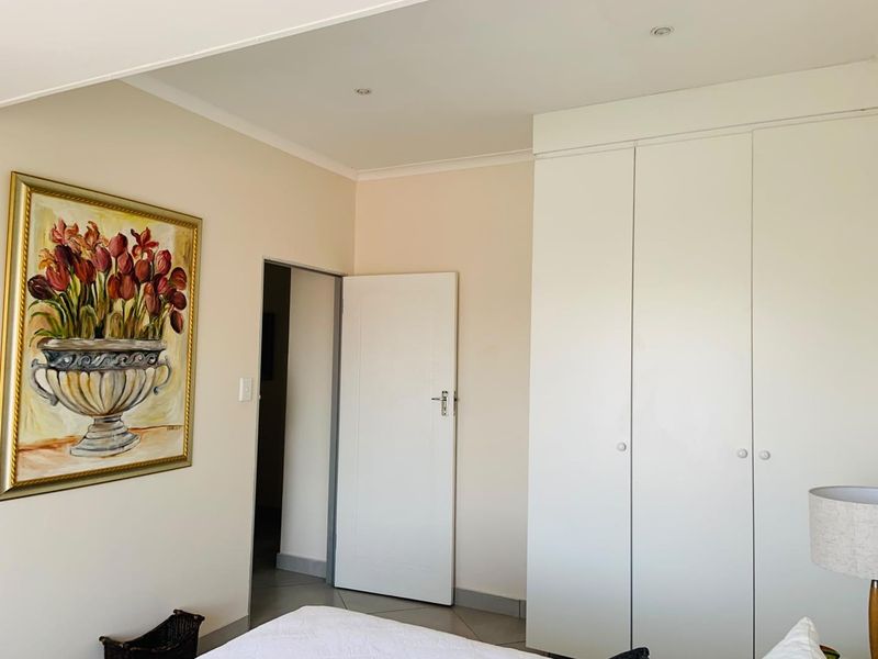 A well-maintained bedroom featuring neutral walls, tiled flooring, recessed ceiling lighting, and ample built-in cupboard storage.