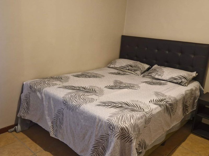 A standard bedroom featuring tiled flooring and neutral wall finishes.