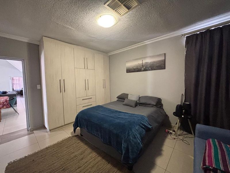 A bedroom featuring built-in cupboards, tiled flooring, and a coved ceiling, offering a functional and neutral space.