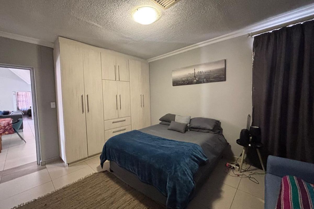 A bedroom featuring built-in cupboards, tiled flooring, and a coved ceiling, offering a functional and neutral space.