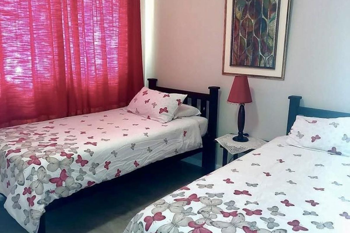 A functional bedroom featuring light-toned laminate flooring and neutral wall finishes, providing a comfortable space for rest.