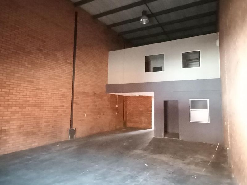 Spacious industrial warehouse unit featuring high ceilings, exposed brick walls, and a mezzanine level suitable for office or storage use.