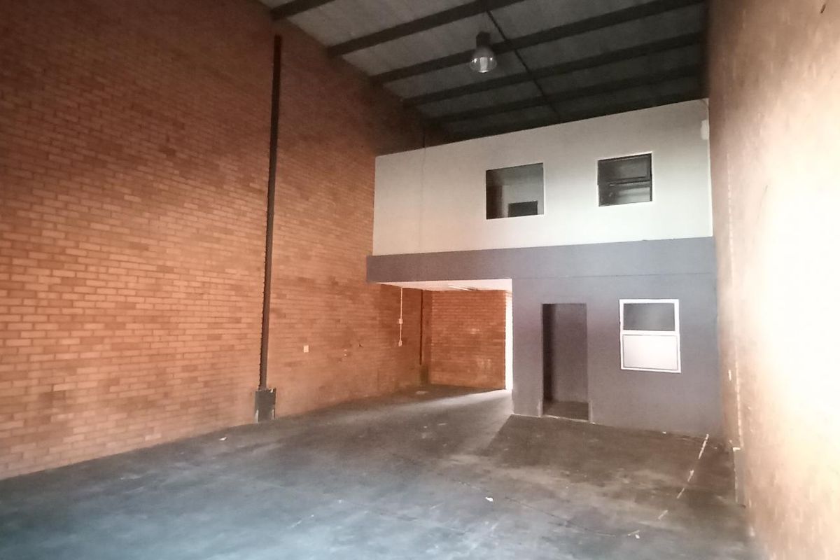 Spacious industrial warehouse unit featuring high ceilings, exposed brick walls, and a mezzanine level suitable for office or storage use.