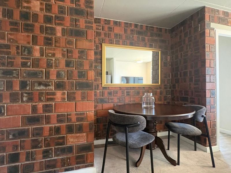 A dining area featuring a prominent exposed brick wall, providing a rustic texture and character to the interior space.