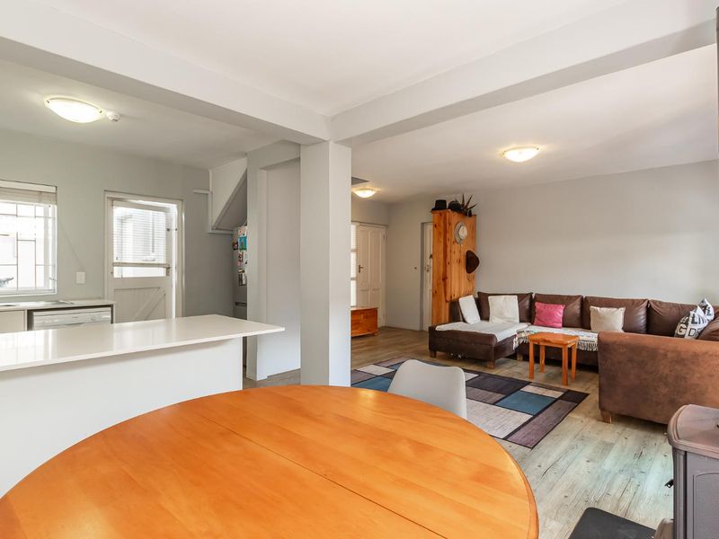 Open plan living and kitchen area featuring laminate flooring, a central island, and a wood-burning stove, creating a functional and connected living space.