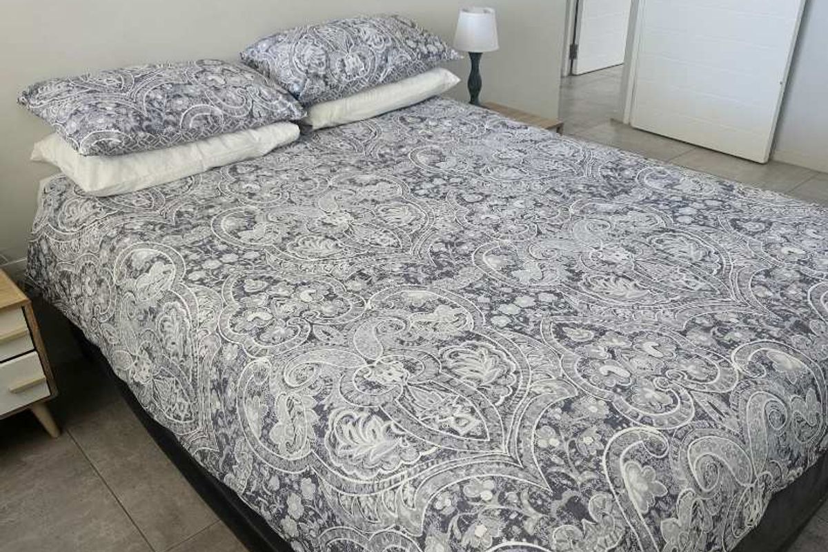A well-maintained bedroom featuring neutral wall tones, modern tiled flooring, and a clean internal door finish.