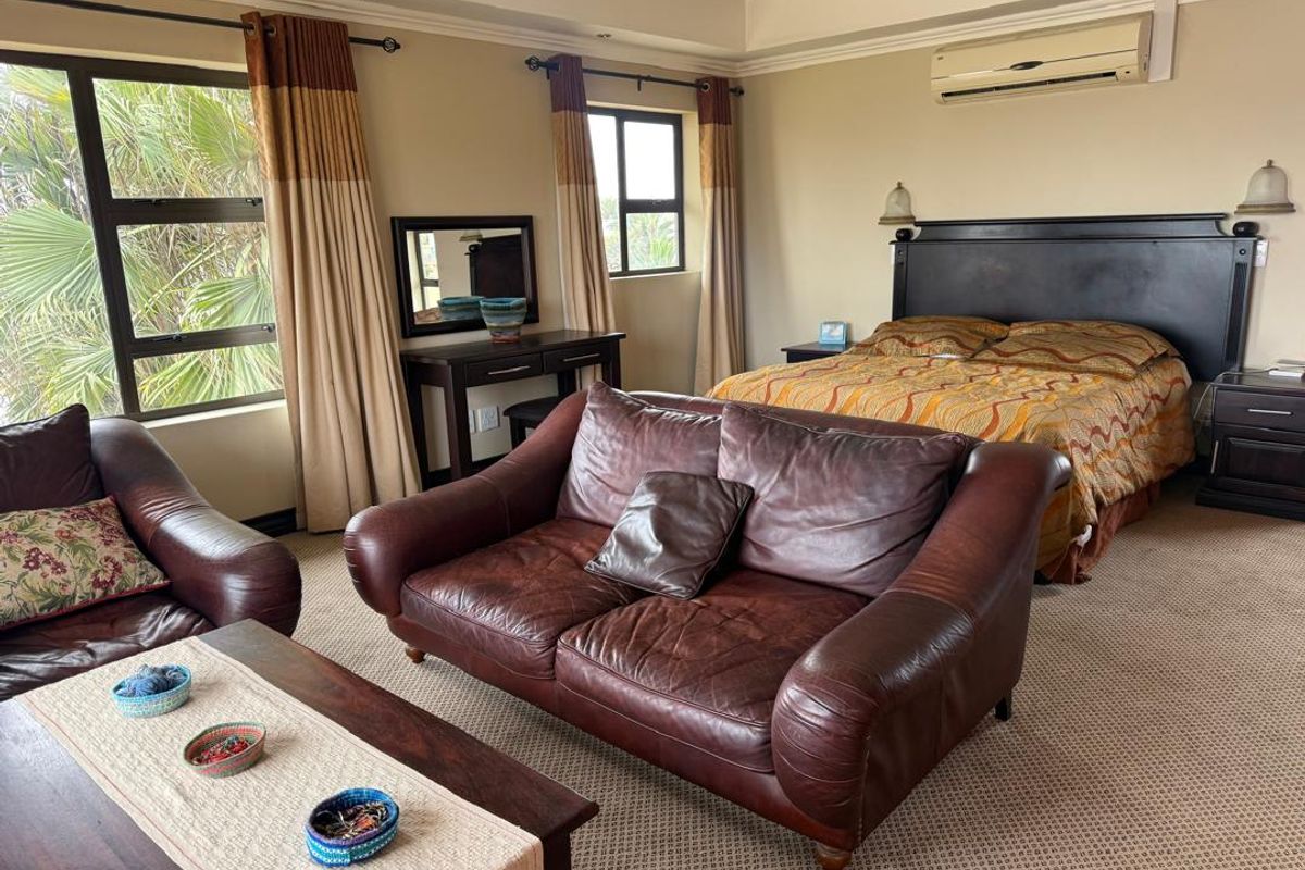 Spacious bedroom featuring carpeted flooring, split-system air conditioning, and large windows providing natural light.