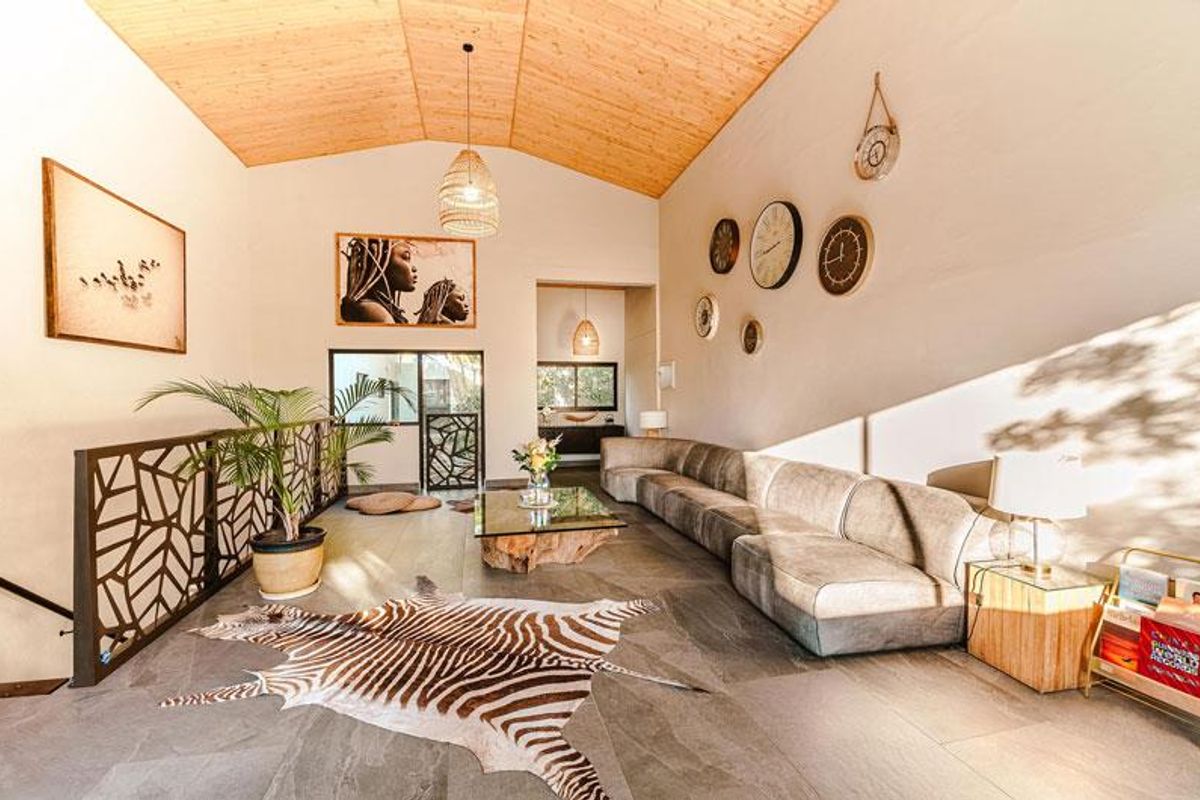 Spacious living area featuring a high vaulted timber ceiling, modern tiled flooring, and a decorative metal balustrade overlooking the lower level.