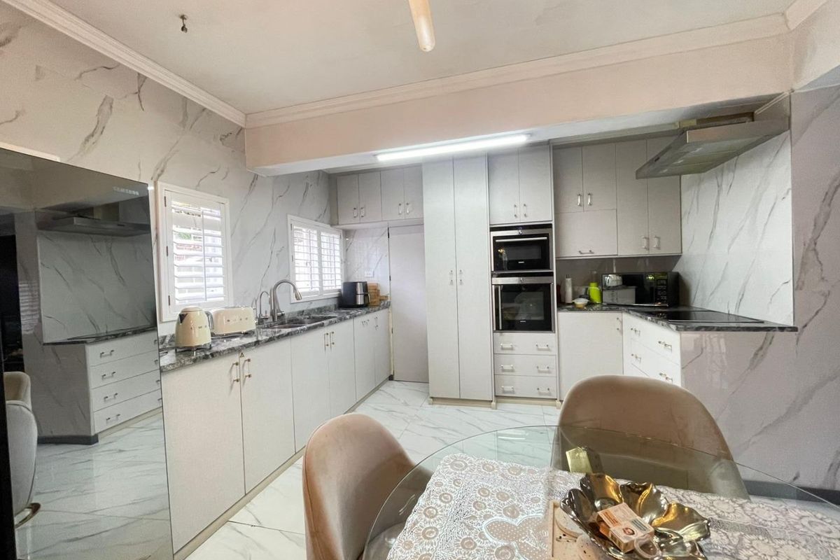 Modern kitchen featuring marble-look finishes, extensive built-in cabinetry, integrated appliances, and tiled flooring, offering a clean and functional culinary space.