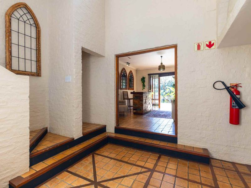 Spacious entrance hall featuring terracotta tile flooring, a decorative arched window, and a built-in staircase leading to the upper level.
