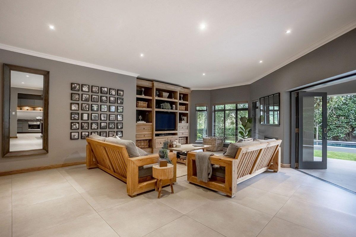 Spacious living room featuring built-in wooden cabinetry, recessed downlighting, large format floor tiles, and seamless access to the outdoor patio area.