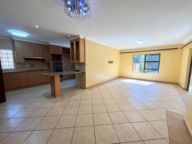 Spacious open-plan living and kitchen area featuring tiled flooring, built-in cabinetry, granite countertops, and integrated oven, offering a bright and functional layout.