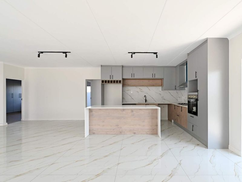 Modern open-plan kitchen featuring a central island, sleek grey and wood-tone cabinetry, marble-look splashback, and high-quality porcelain floor tiles.