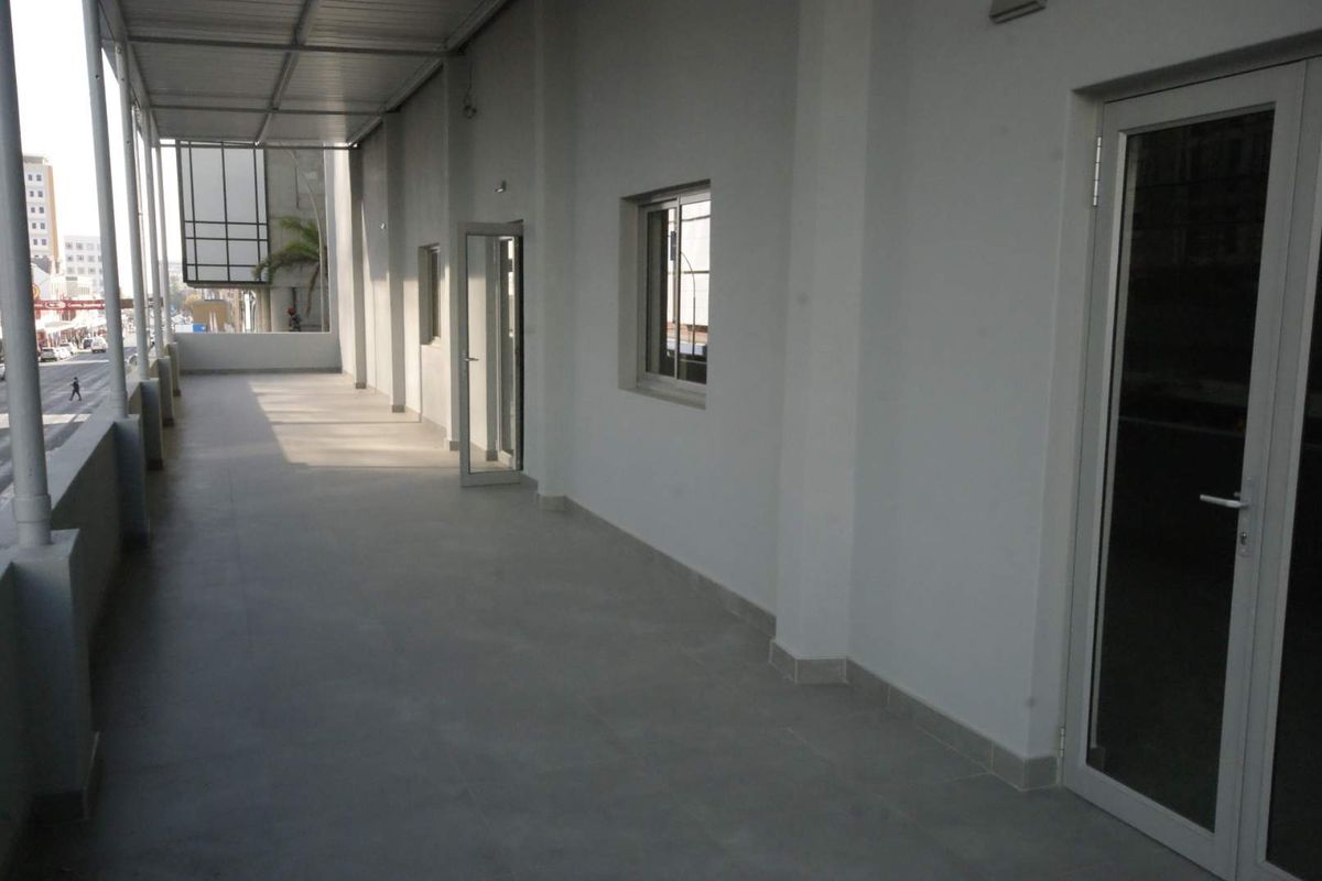 A spacious, covered balcony featuring tiled flooring and modern aluminium-framed glass doors, providing access to the interior office or commercial space.