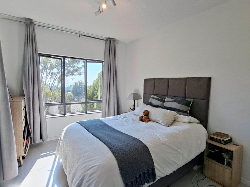 A bright and well-maintained bedroom featuring a large window that allows for natural light and pleasant outdoor views.