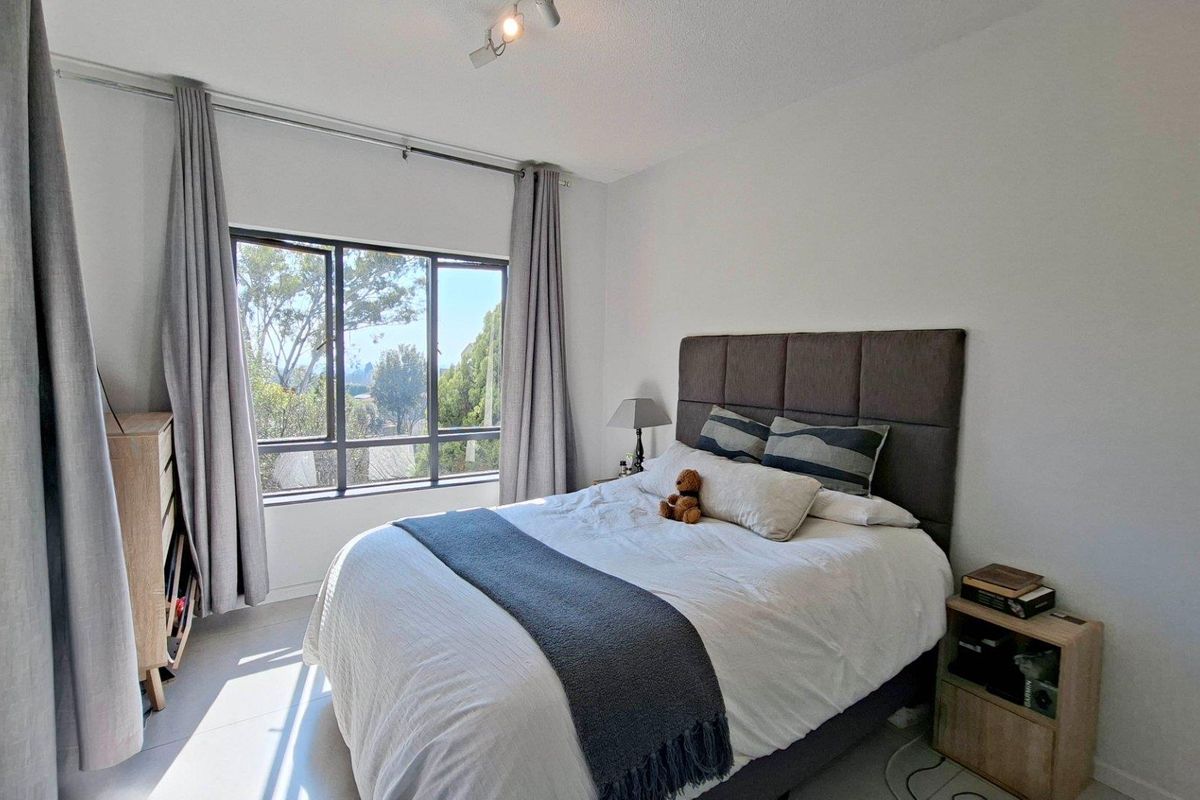 A bright and well-maintained bedroom featuring a large window that allows for natural light and pleasant outdoor views.