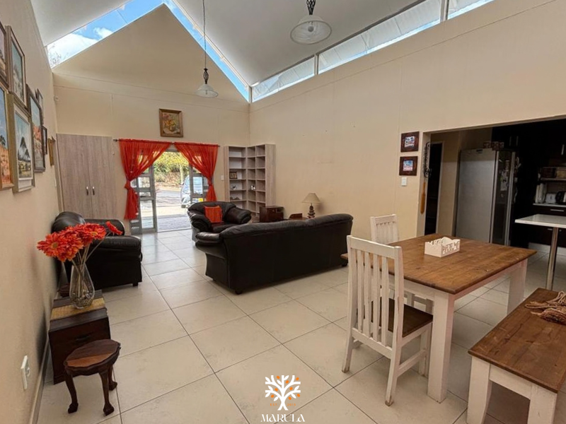 Spacious open-plan living and dining area featuring a high vaulted ceiling with clerestory windows, tiled flooring, and integrated storage cabinetry.
