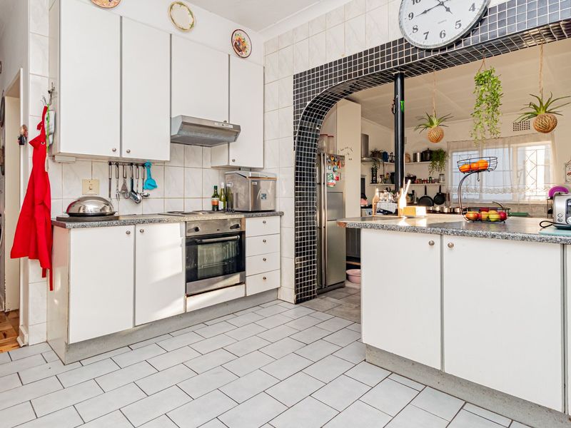 A functional kitchen featuring white cabinetry, stone countertops, a built-in oven, and a distinctive tiled archway leading to an adjacent space.