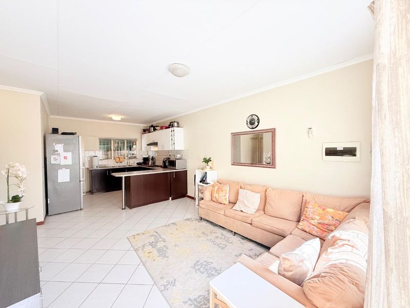 Open-plan living area featuring tiled flooring and a functional kitchen with built-in cabinetry and counter space, creating a versatile living and dining environment.