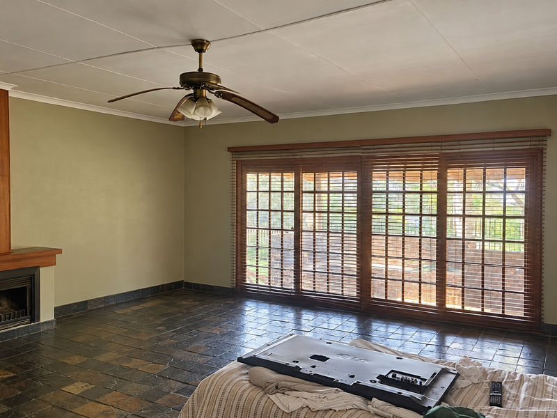 Spacious living room featuring slate tile flooring, a built-in fireplace with wooden surround, and large sliding glass doors leading to the exterior.