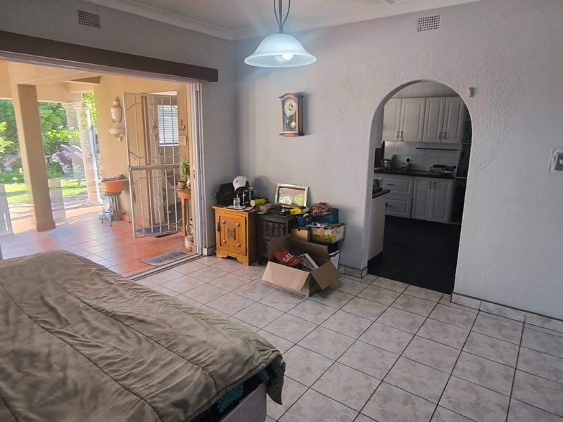 Open plan living area featuring tiled floors, an arched entryway to the kitchen, and large sliding doors providing access to the outdoor patio.