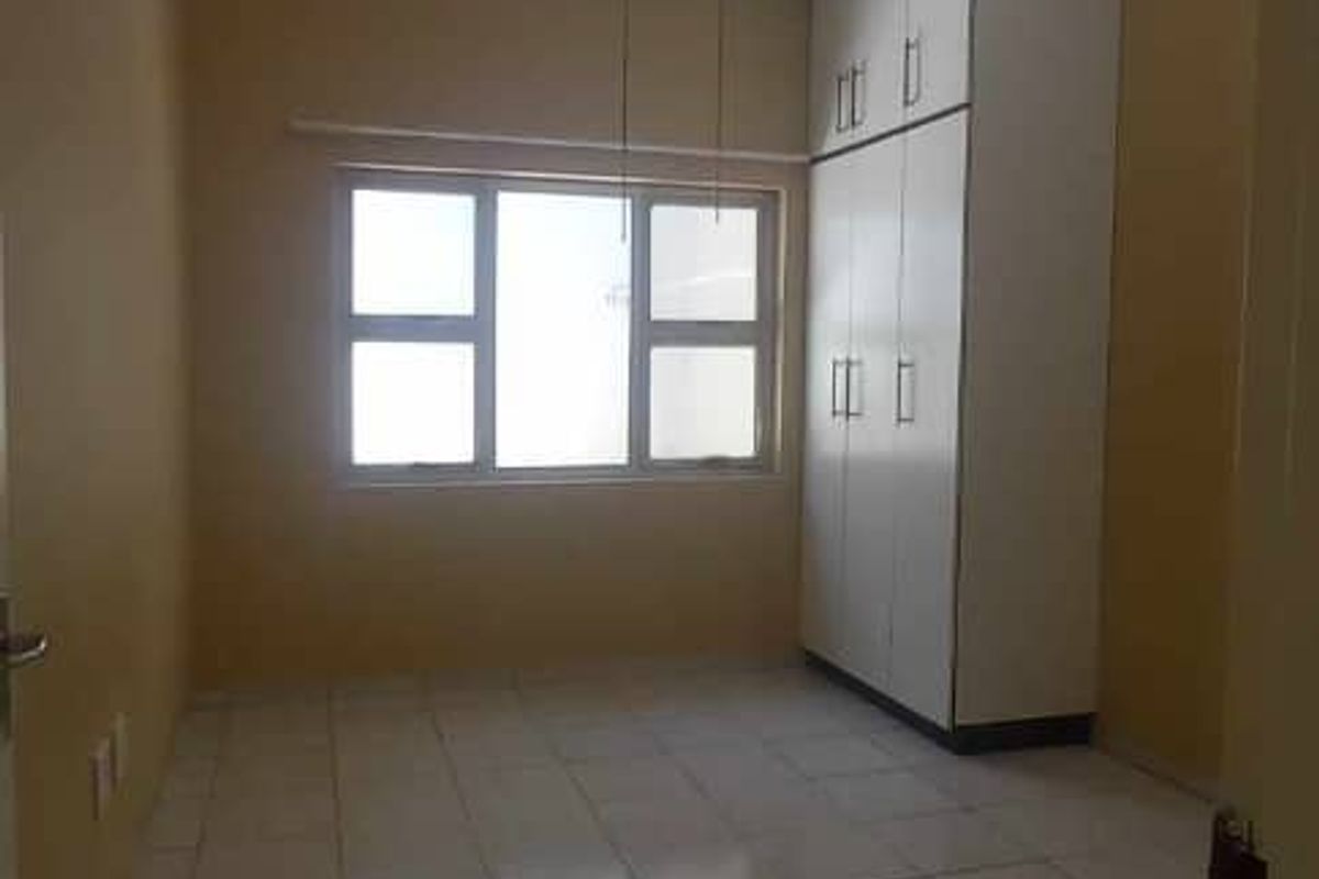 A bedroom featuring tiled flooring, a built-in wardrobe, and a ceiling fan.