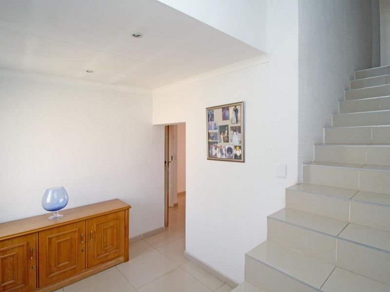 A bright entrance hallway featuring tiled flooring and a staircase leading to the upper level, providing access to adjacent rooms.