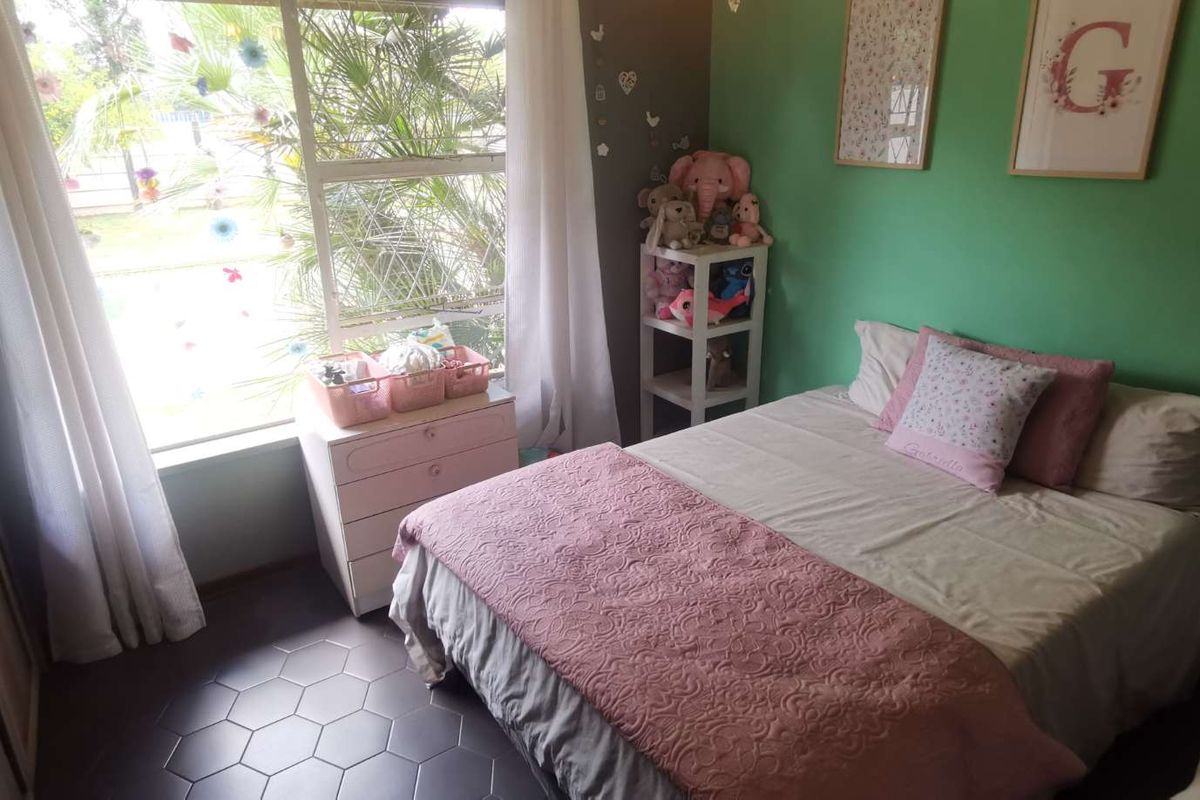 A bedroom featuring tiled flooring and a built-in wardrobe, with natural light provided by a large window.