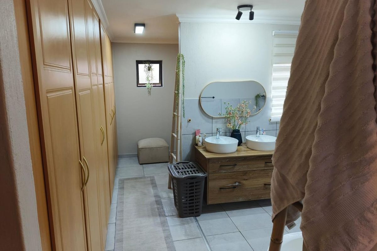 A well-appointed bathroom featuring a double vanity with vessel sinks, modern cabinetry, and extensive built-in wardrobe storage.