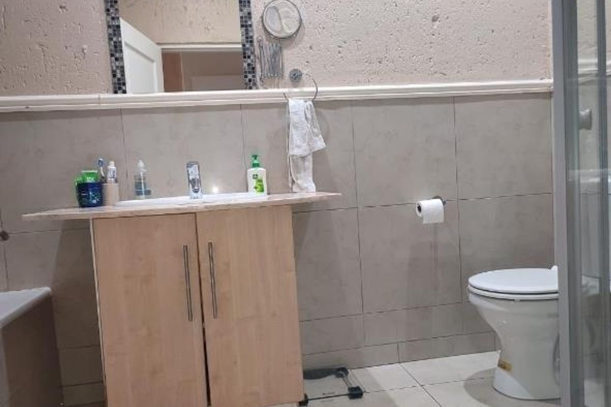 A functional bathroom featuring a vanity cabinet with a basin, a toilet, and tiled wall finishes.