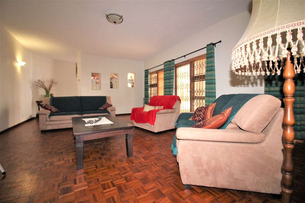 Spacious living room featuring classic parquet wood flooring, large windows with security gates, and decorative wall niches.