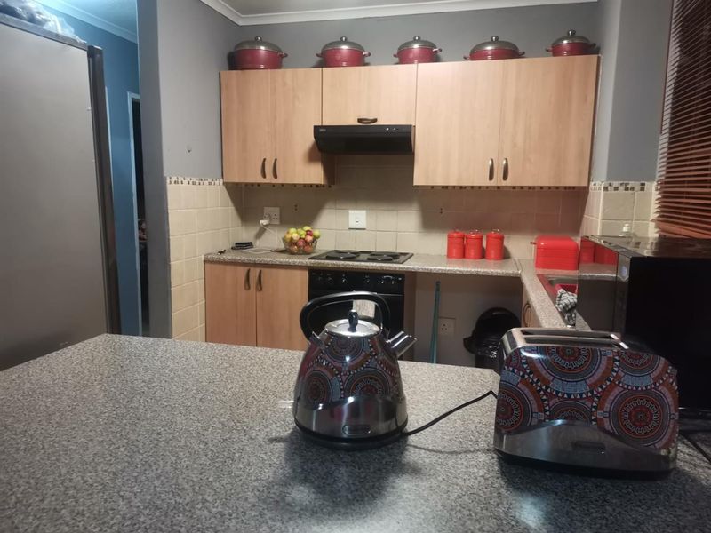 A functional kitchen featuring laminate cabinetry, granite countertops, a built-in oven, and an electric hob with an extractor fan.