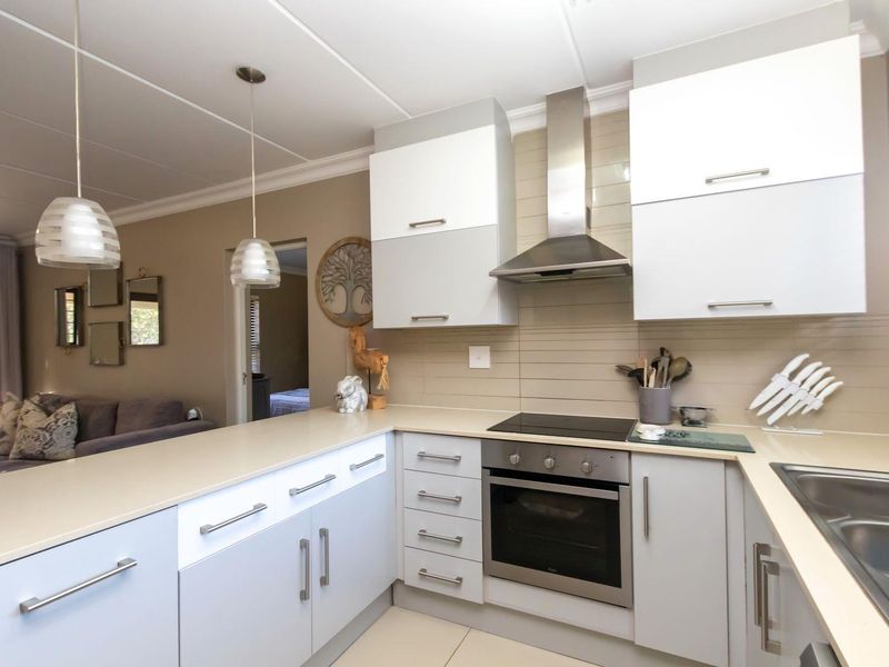 Modern open-plan kitchen featuring sleek two-tone cabinetry, integrated stainless steel appliances, tiled backsplash, and a functional breakfast bar overlooking the living area.