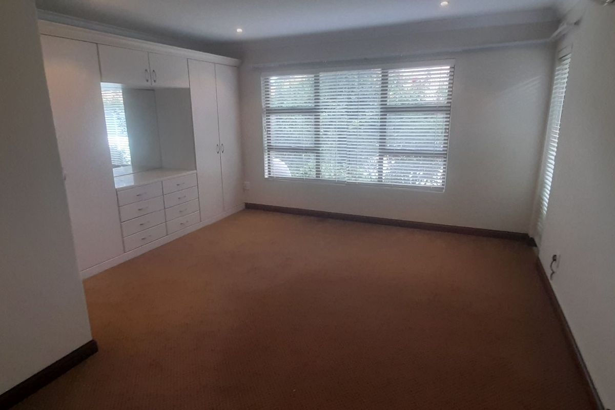 Spacious bedroom featuring built-in cabinetry with integrated vanity and large windows with fitted blinds.