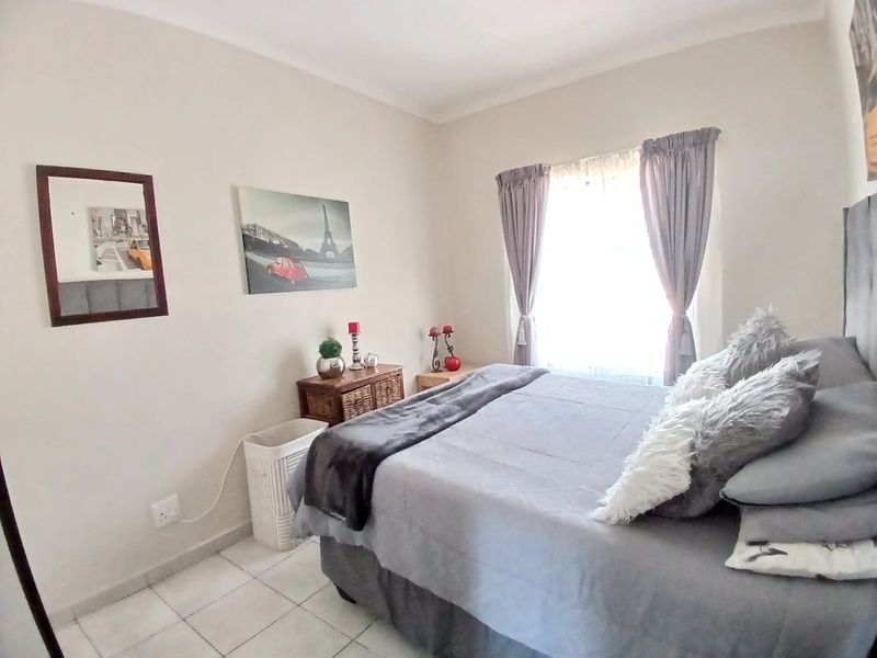 A well-lit bedroom featuring neutral wall tones and tiled flooring, providing a comfortable and functional living space.