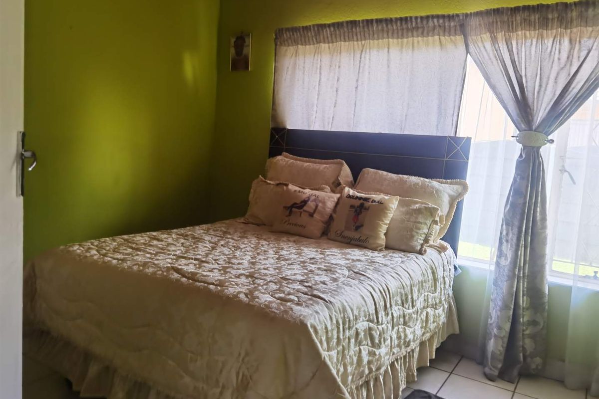 A bedroom featuring tiled flooring and a wall-mounted air vent, providing a functional space with natural light.