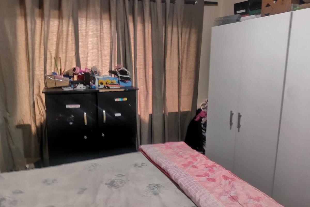 A bedroom featuring a built-in wardrobe and window with curtain rails, providing a functional space for rest.