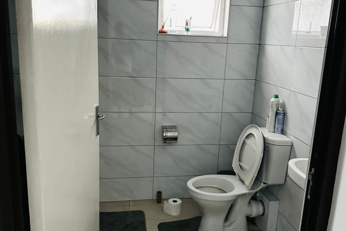 A compact bathroom featuring floor-to-ceiling marble-look wall tiles, a standard toilet, and a small wall-mounted basin.