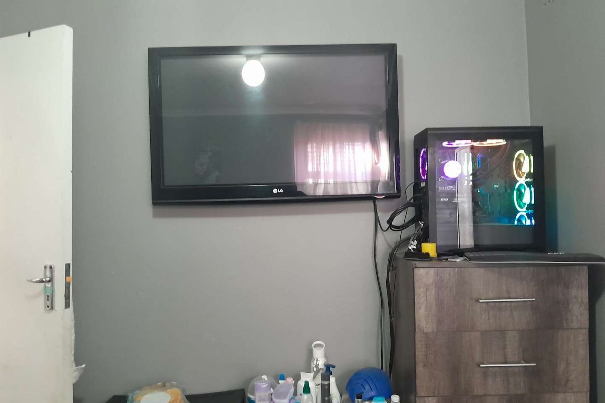 A bedroom interior featuring a wall-mounted television and a dedicated space for a computer setup.