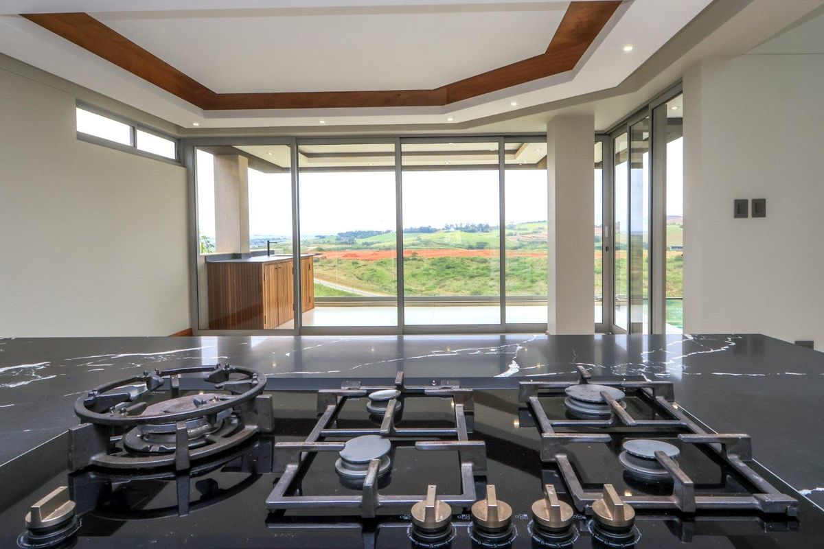 Modern kitchen featuring a sleek black stone countertop with an integrated gas hob, overlooking expansive rural views through large sliding glass doors.