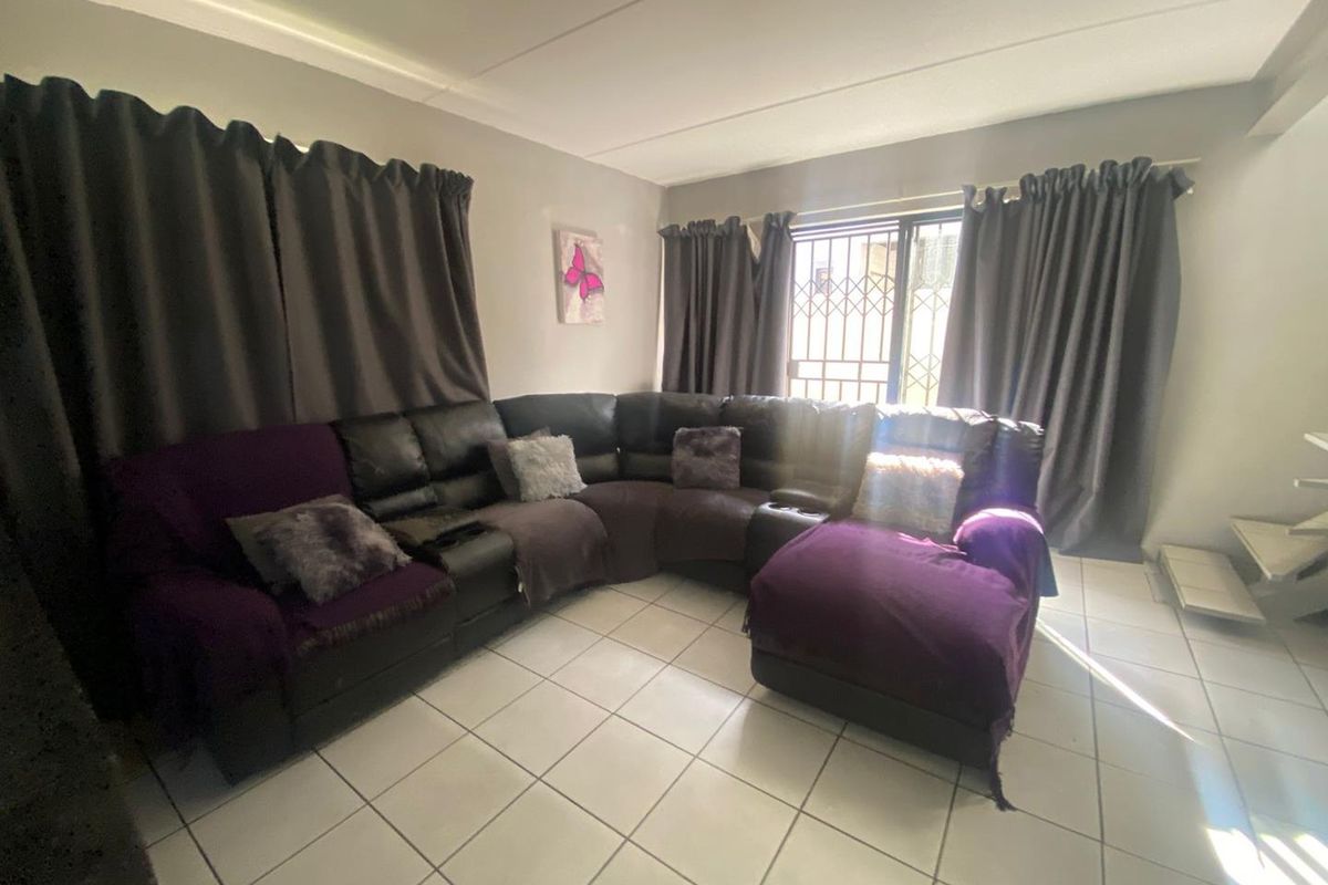 A living room featuring tiled flooring and a security gate on the window.