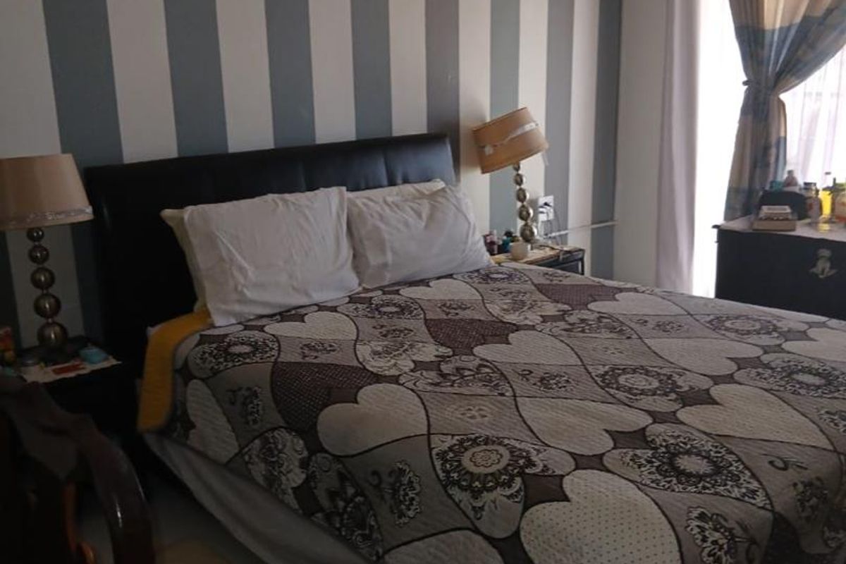 A bedroom featuring a wall-mounted air conditioning unit and striped wallpaper.