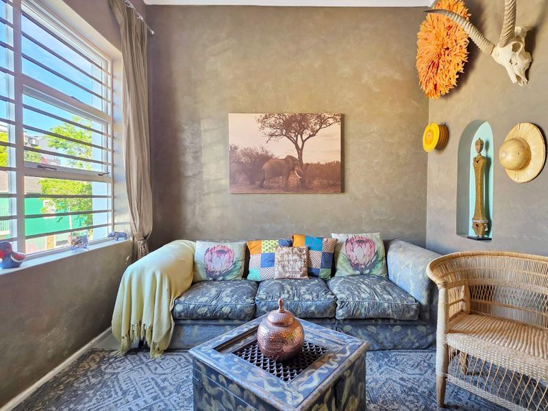 A cozy living room featuring a textured wall finish, a built-in wall niche, and a large louvre window allowing natural light.