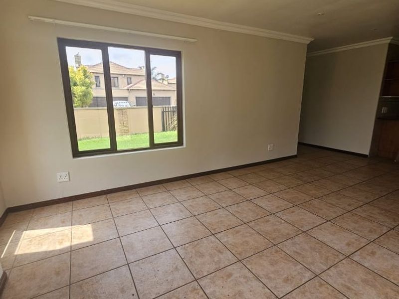 A spacious, empty living area featuring neutral walls, tiled flooring, and recessed lighting, offering a blank canvas for interior design.
