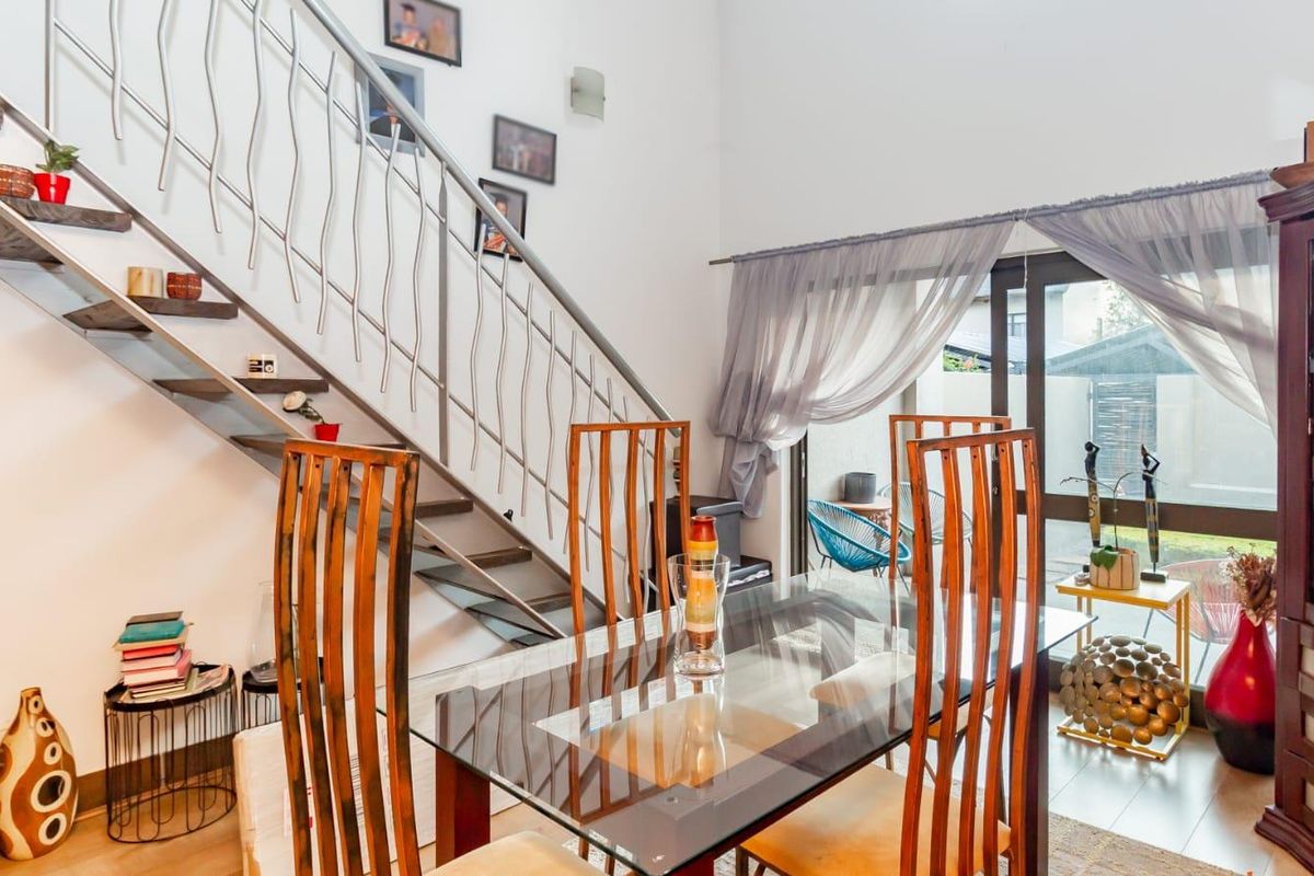 Open-plan living area featuring a modern staircase with metal balustrade, laminate flooring, and large sliding glass doors providing access to the outdoor space.