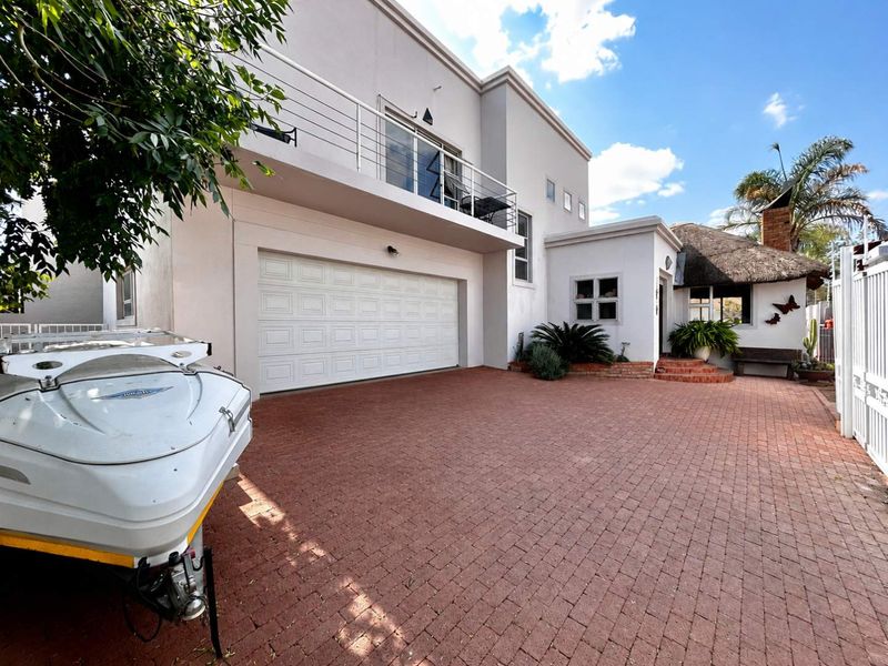 Front exterior view of the property featuring a paved driveway, double garage, and an upper-level balcony with metal railings.